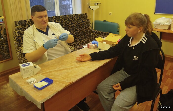 Нажмите для увеличения За столом медицинский работник, осуществляющий тест на ВИЧ у сидящей напротив студентки колледжа